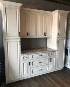 an empty kitchen with white cabinets and granite counter tops in the middle of the room