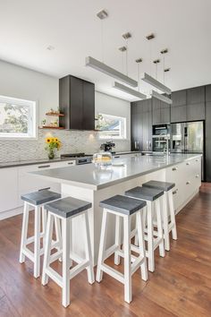 a large kitchen with an island and bar stools in front of the countertop