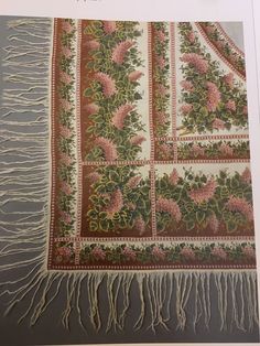 an old rug with pink flowers and green leaves on it's border, hanging from the wall