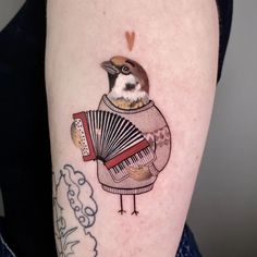 a bird with an accordion tattoo on the arm