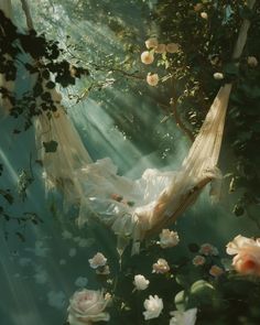 a woman laying in a hammock surrounded by flowers and greenery with sunlight streaming through the trees