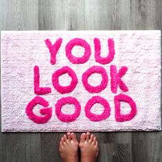 someone is standing on the floor in front of a pink rug that says you look good