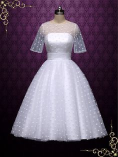 a white wedding dress on a mannequin stand in front of a purple background