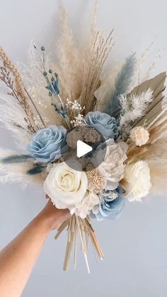 someone is holding a bouquet with flowers and feathers