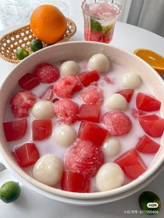 a bowl filled with watermelon and other fruit next to a glass of orange juice