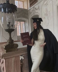 a woman in a graduation gown holding a book