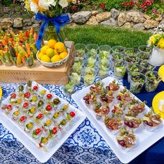 an assortment of food is displayed on plates and trays in front of a blue table cloth