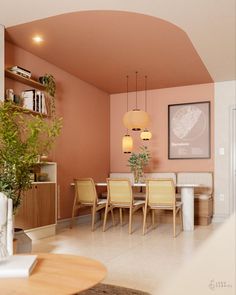 a living room filled with furniture and a dining table surrounded by potted plants on top of a hard wood floor