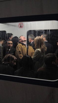 a group of people standing on a subway train looking out the window at something in the distance