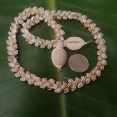 a necklace with shells and a coin on it