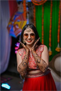 a woman with henna on her hands and face painted in red, white and gold