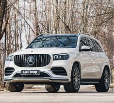 a white mercedes gls parked in front of some trees