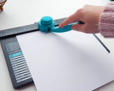 a person is using a ruler to cut paper on a piece of paper with scissors