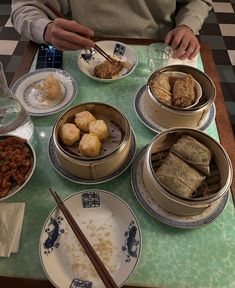 a table topped with bowls filled with food next to chopsticks and water glasses