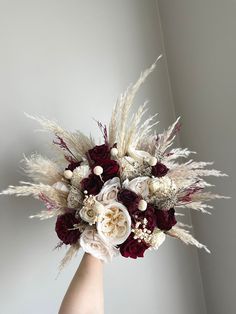 a woman's hand holding a bouquet of white and red flowers