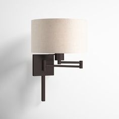 a wall light with a white shade on the side and a black metal frame around it