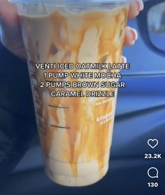 a person holding up a cup with caramel flavored drink in it's hand