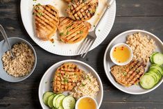 grilled chicken, rice and cucumbers are served on plates with silverware