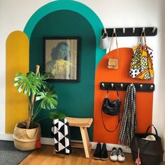 a colorful entryway with an arch, potted plant and purses hanging on hooks