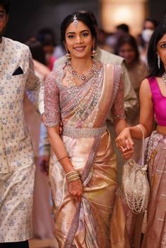 a woman in a sari walking down the aisle with another woman wearing a suit and tie