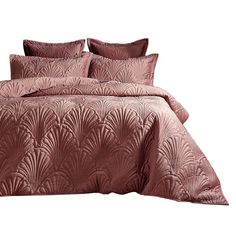 a bed with pink comforter and pillows on top of it, in front of a white background