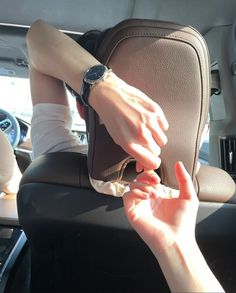 a woman sitting in the back seat of a car with her hand on an arm rest