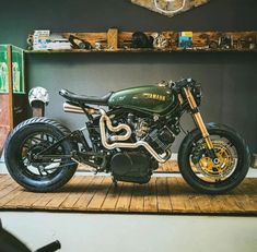 a green motorcycle parked on top of a wooden floor next to a shelf filled with items