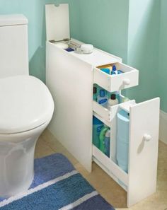 a white toilet sitting in a bathroom next to a sink and a blue rug on the floor