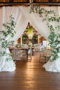 an indoor wedding venue with white drapes and greenery