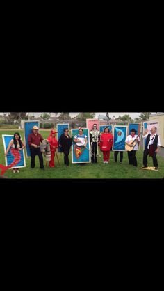 a group of people standing next to each other in front of pictures on the grass