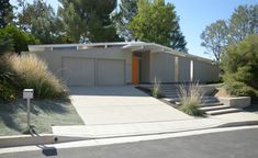 a modern house with landscaping and trees in the background