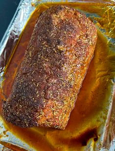 a piece of meat sitting on top of tin foil covered in mustard and seasoning