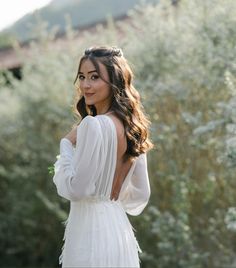 a woman in a white dress is posing for the camera