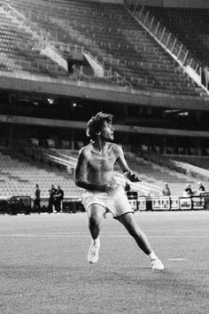 a shirtless man is playing tennis in an empty stadium with people watching from the bleachers