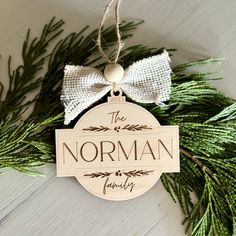 a wooden ornament hanging from a pine tree with the name norman written on it