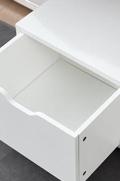 an open drawer on top of a white dresser next to a black carpeted floor