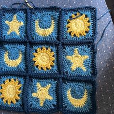 a crocheted square with sun and moon designs on the sides, sitting on a blue surface