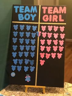 a black board with pink and blue baby ones on it that says team boy and team girl