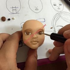 a person is making a doll head out of clay