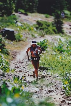 a woman running down a trail in the woods