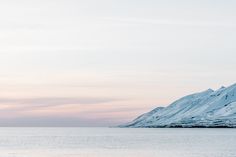 the mountains are covered in snow near the ocean