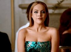 a woman in a strapless green dress is sitting at a table and looking off to the side