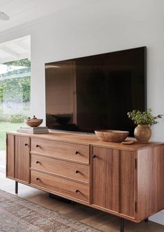 a large flat screen tv mounted on top of a wooden entertainment center in a living room