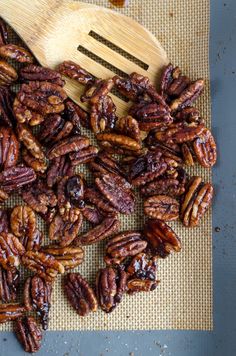 a pile of pecans sitting on top of a table next to a wooden spoon