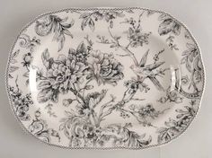 a black and white floral plate with silver trimmings on the edge, holding two forks