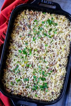 a casserole dish with meat, cheese and parsley in a black pan