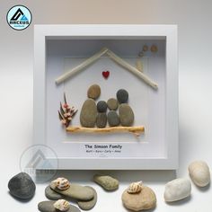 some rocks are arranged in a white frame with a small house made out of them