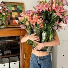 a woman holding two vases filled with flowers