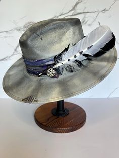 This is a gorgeous stiff brim painted fedora accented with purple, silver, and black colors. This hat is a size large with an elastic inner band for the most comfortable fit. Please see size chart in the pictures. Adjustable Purple Brimmed Fedora, Adjustable Wide Brim Fedora With Feather Trim, Adjustable Wide Brim Purple Fedora, Adjustable Wide-brim Fedora With Feather Trim, Adjustable Fedora With Feather Trim And Curved Brim, Adjustable Brimmed Fedora With Feathers, Adjustable Fedora With Feather Trim For Kentucky Derby, Adjustable Purple Fedora With Short Brim, Purple Adjustable Short Brim Fedora