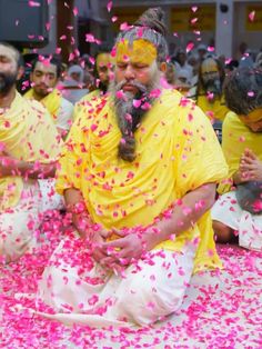 a group of men sitting on top of a floor covered in pink confetti